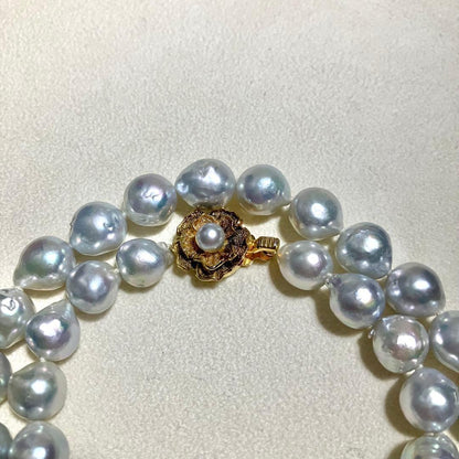 Akoya pearl necklace featuring large 9.0mm round pearls with gold hardware and flower-shaped clasp in blue-gray tone