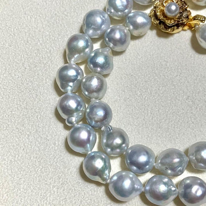 Akoya pearl necklace featuring large 9.0mm round pearls with gold hardware and flower-shaped clasp in blue-gray tone