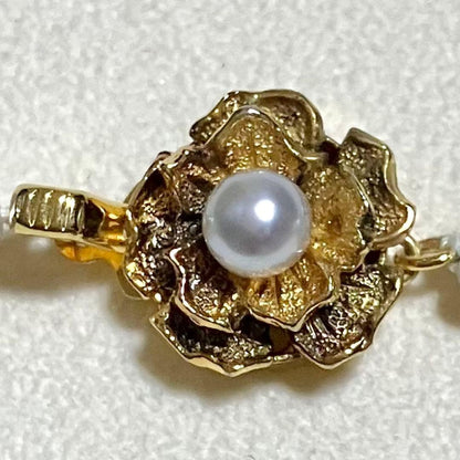Akoya pearl necklace featuring large 9.0mm round pearls with gold hardware and flower-shaped clasp in blue-gray tone