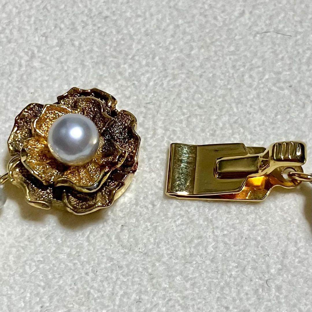 Akoya pearl necklace featuring large 9.0mm round pearls with gold hardware and flower-shaped clasp in blue-gray tone