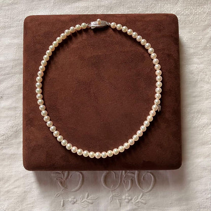 MIKIMOTO pearl choker necklace with 63 round pearls and silver M engraved clasp displayed with original box