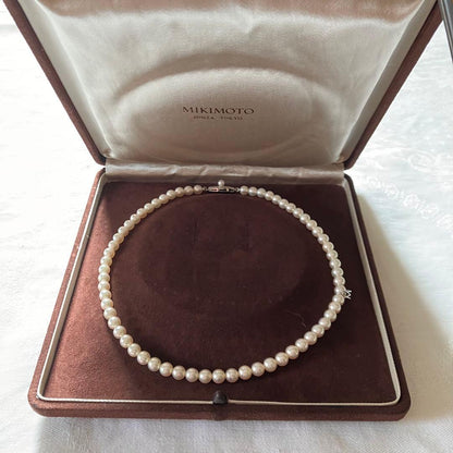 MIKIMOTO pearl choker necklace with 63 round pearls and silver M engraved clasp displayed with original box