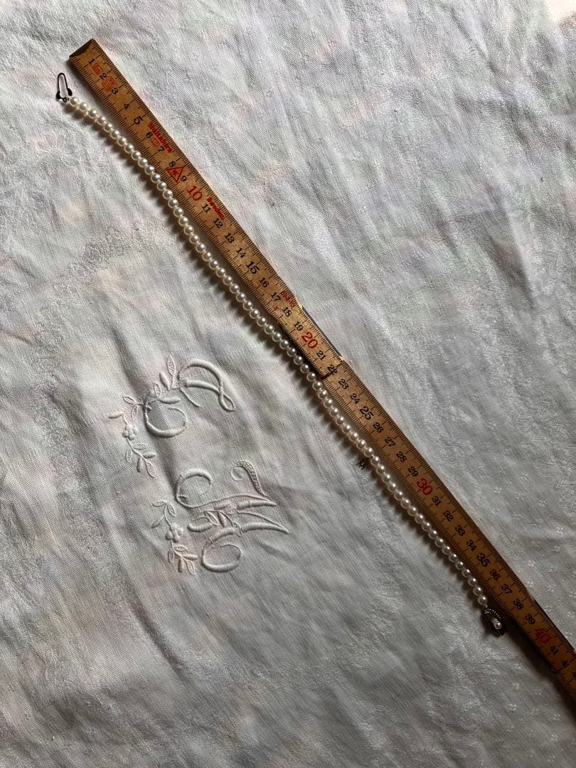 MIKIMOTO pearl choker necklace with 63 round pearls and silver M engraved clasp displayed with original box
