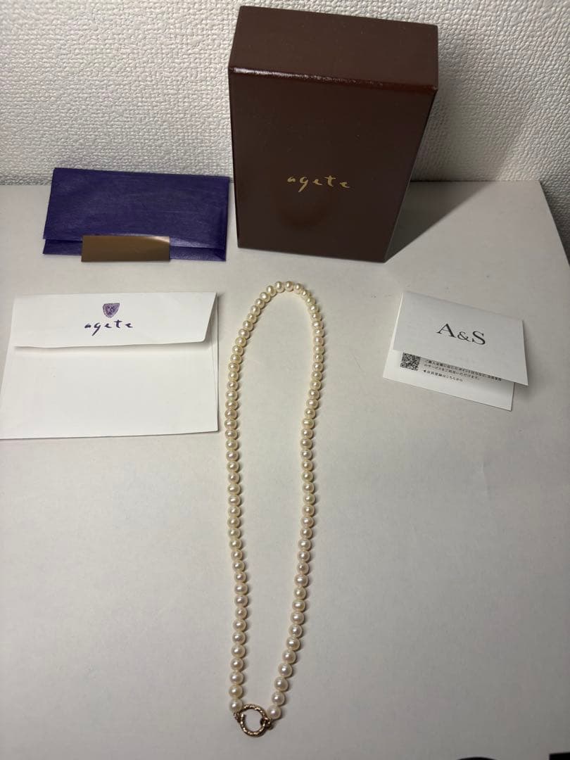 Agete pearl necklace featuring lustrous freshwater pearls displayed with gift box and guarantee card