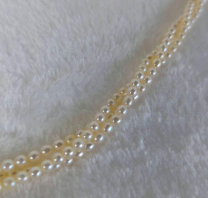 Tazaki Pearl 3-Strand necklace with baby freshwater pearls and silver case on white background