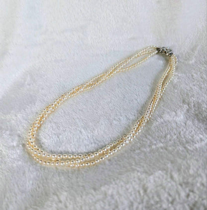 Tazaki Pearl 3-Strand necklace with baby freshwater pearls and silver case on white background
