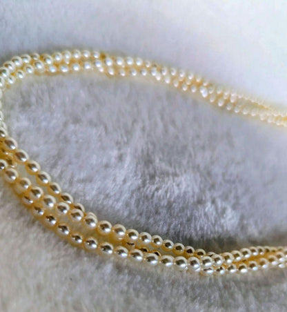 Tazaki Pearl 3-Strand necklace with baby freshwater pearls and silver case on white background