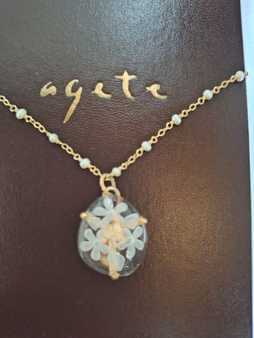agete flower motif necklace with gold flower pendant and metal chain displayed with dedicated box