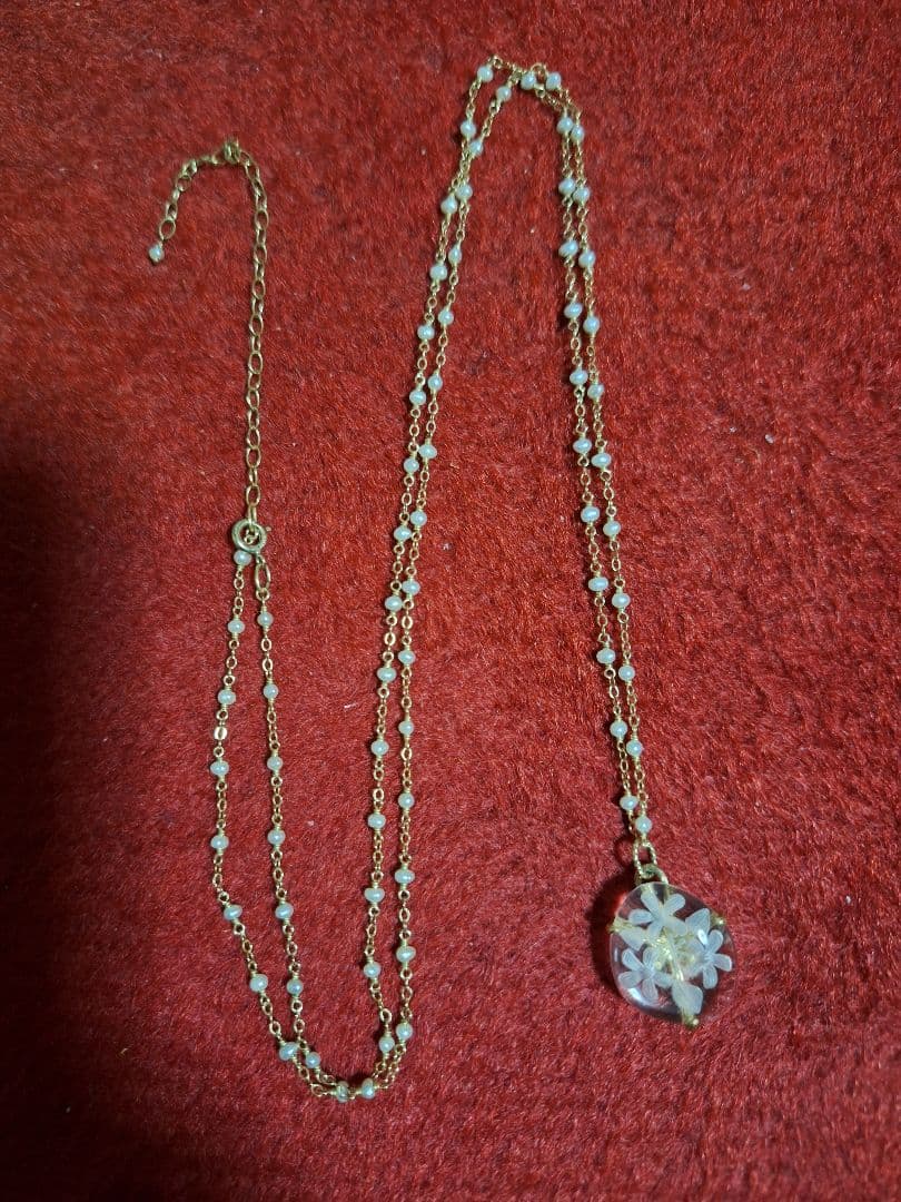 agete flower motif necklace with gold flower pendant and metal chain displayed with dedicated box
