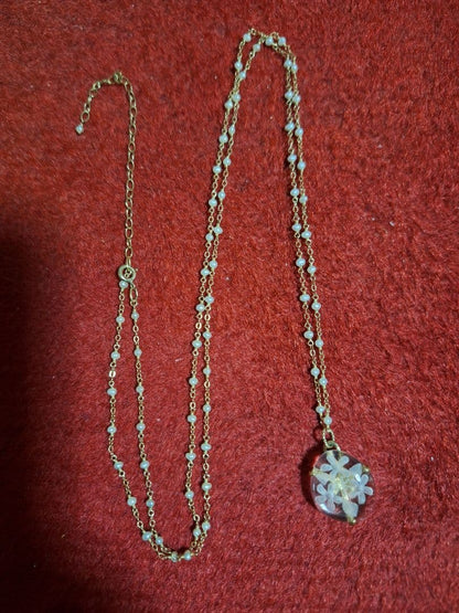agete flower motif necklace with gold flower pendant and metal chain displayed with dedicated box