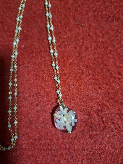 agete flower motif necklace with gold flower pendant and metal chain displayed with dedicated box