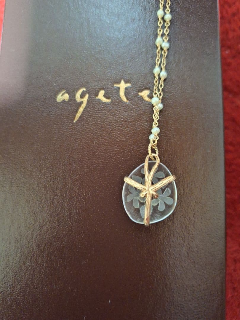 agete flower motif necklace with gold flower pendant and metal chain displayed with dedicated box
