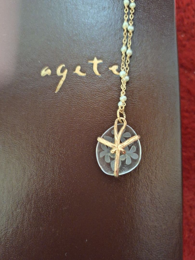 agete flower motif necklace with gold flower pendant and metal chain displayed with dedicated box