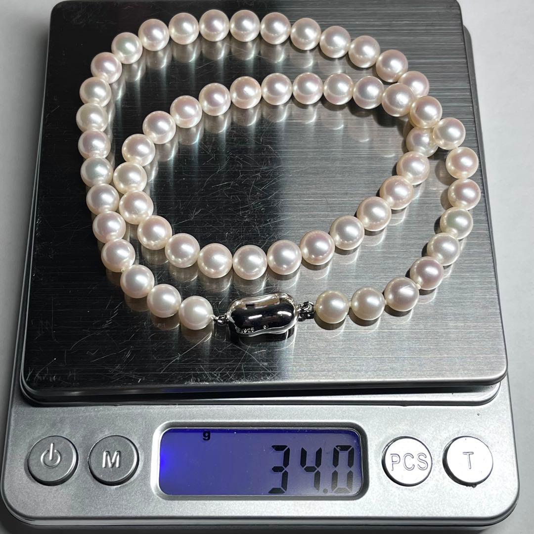 Close-up of Akoya pearl necklace with white pearls showing pink and green interference colors and silver clasp