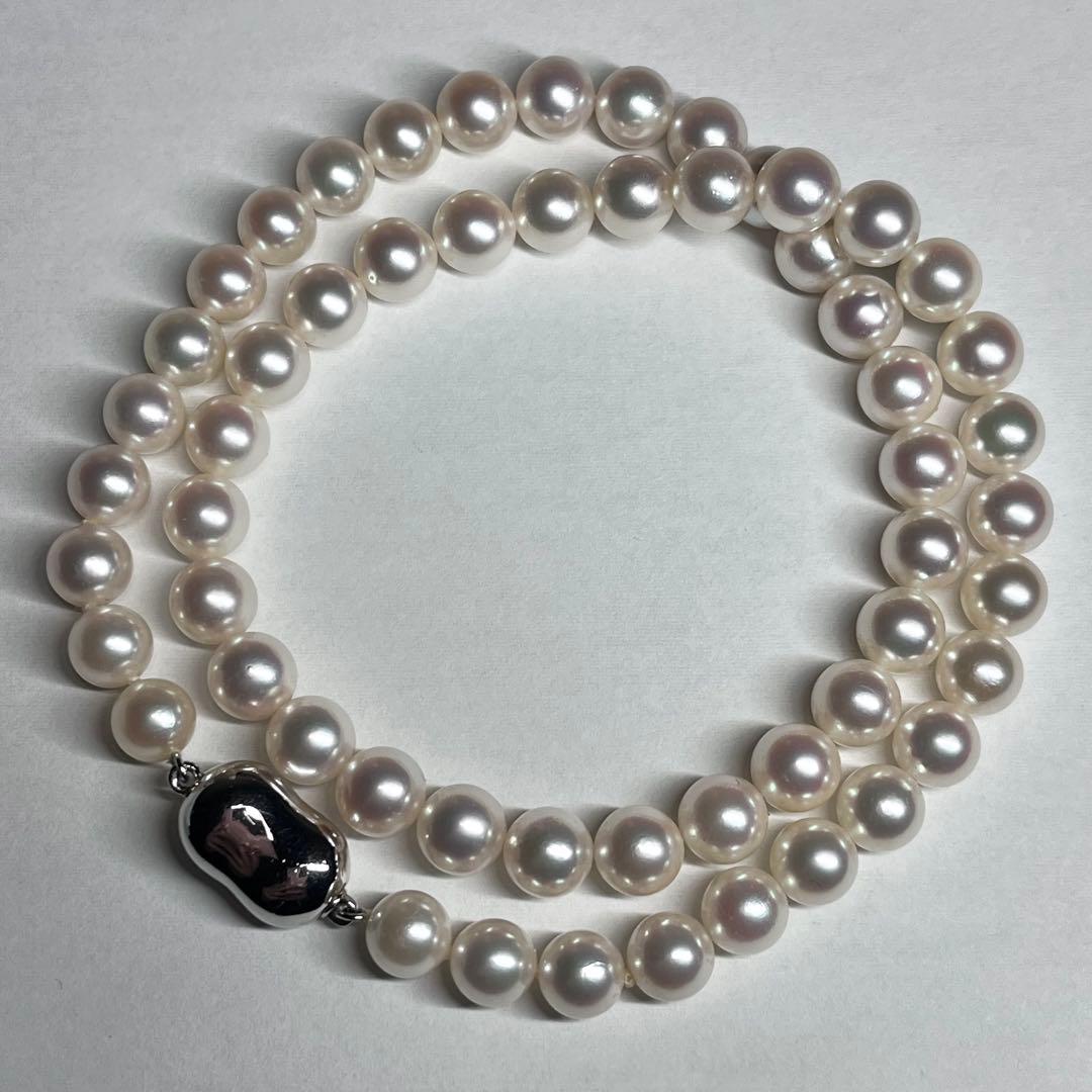 Close-up of Akoya pearl necklace with white pearls showing pink and green interference colors and silver clasp