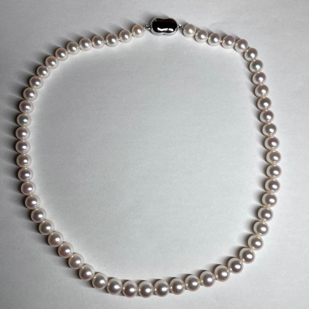 Close-up of Akoya pearl necklace with white pearls showing pink and green interference colors and silver clasp