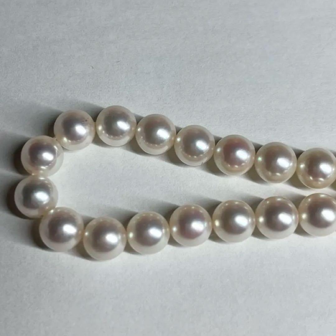 Close-up of Akoya pearl necklace with white pearls showing pink and green interference colors and silver clasp