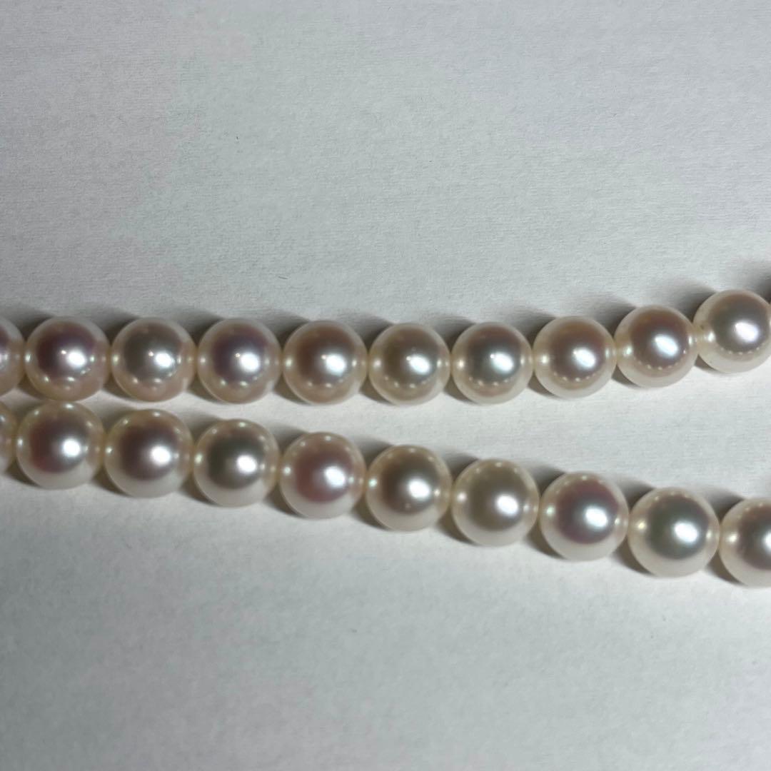 Close-up of Akoya pearl necklace with white pearls showing pink and green interference colors and silver clasp