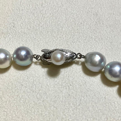 Akoya pearl necklace with 9.0mm pearls laid out showing clasp and identification book