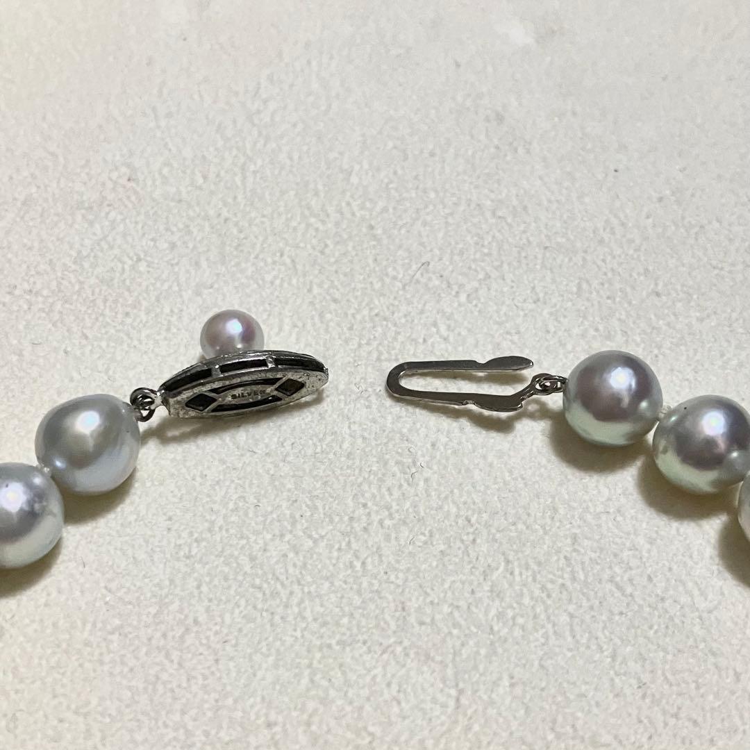 Akoya pearl necklace with 9.0mm pearls laid out showing clasp and identification book