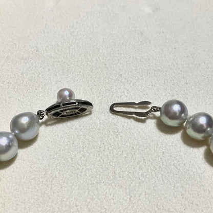 Akoya pearl necklace with 9.0mm pearls laid out showing clasp and identification book