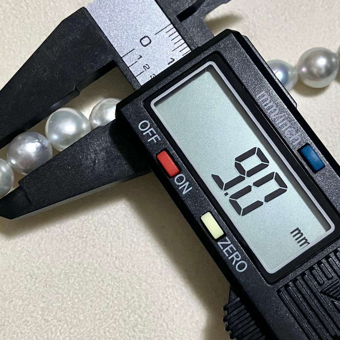 Akoya pearl necklace with 9.0mm pearls laid out showing clasp and identification book