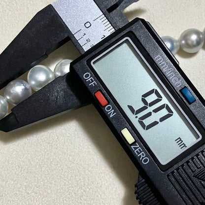 Akoya pearl necklace with 9.0mm pearls laid out showing clasp and identification book