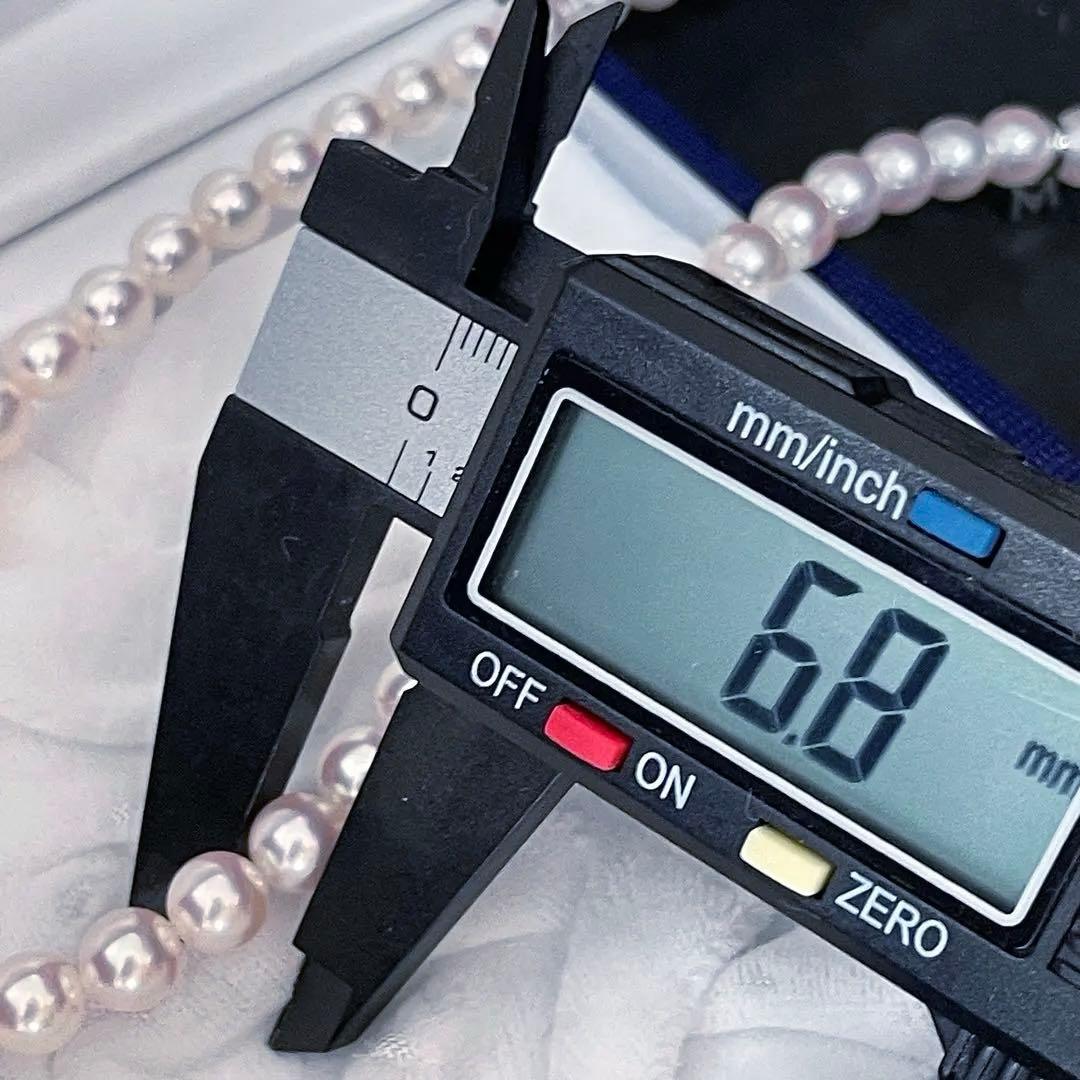 Mikimoto Akoya pearl necklace with 6.5-7mm white pink pearls, M charm, and silver current clasp on a white background