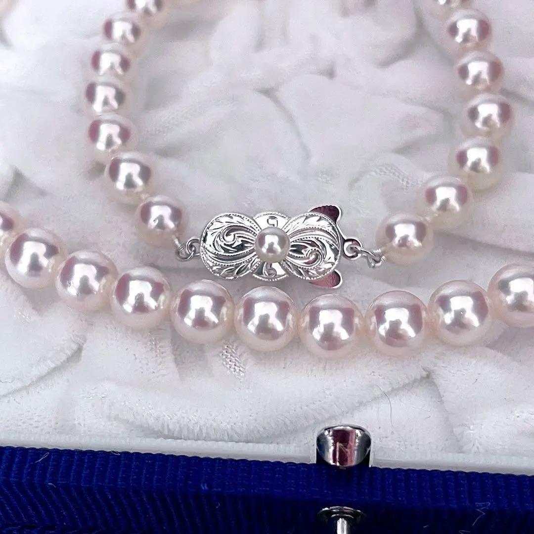 Mikimoto Akoya pearl necklace with 6.5-7mm white pink pearls, M charm, and silver current clasp on a white background