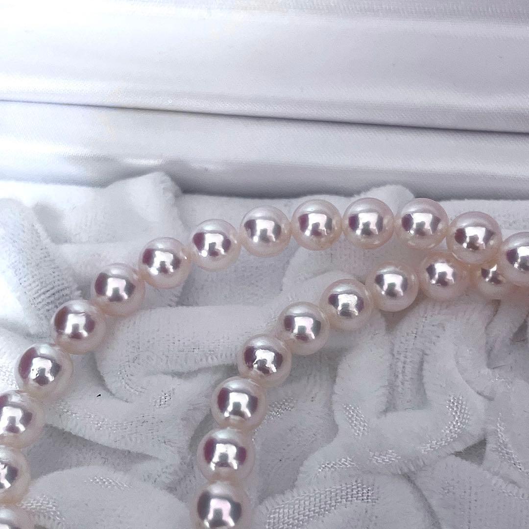 Mikimoto Akoya pearl necklace with 6.5-7mm white pink pearls, M charm, and silver current clasp on a white background
