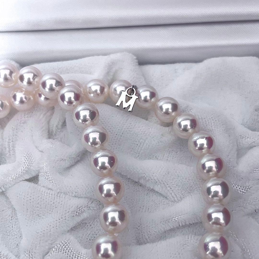 Mikimoto Akoya pearl necklace with 6.5-7mm white pink pearls, M charm, and silver current clasp on a white background