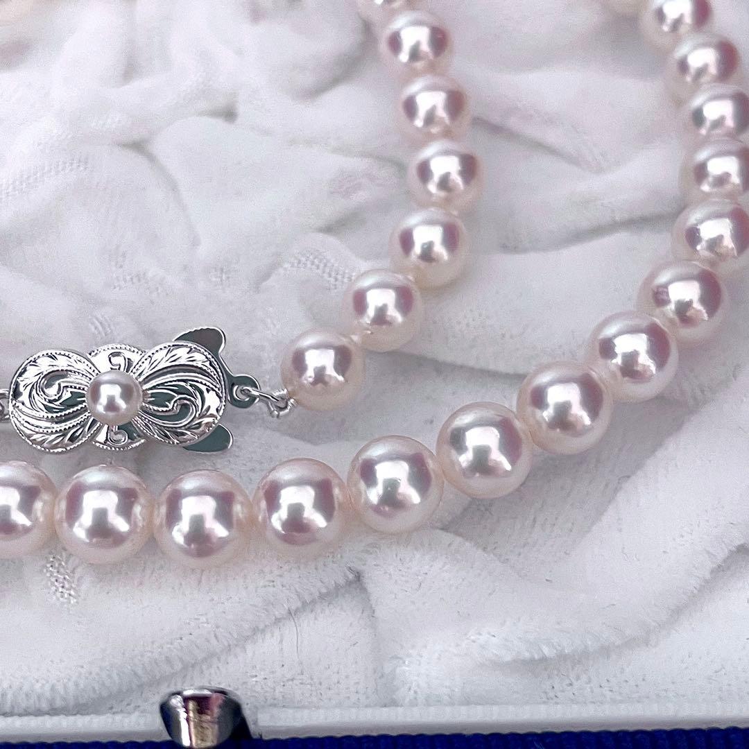 Mikimoto Akoya pearl necklace with 6.5-7mm white pink pearls, M charm, and silver current clasp on a white background