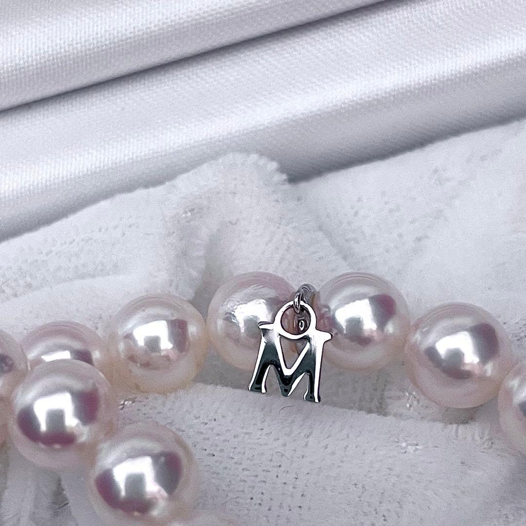 Mikimoto Akoya pearl necklace with 6.5-7mm white pink pearls, M charm, and silver current clasp on a white background