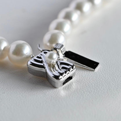 Takatsuki Akoya pearl necklace with 7.5mm round pearls and silver ribbon clasp on a white background