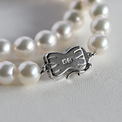 Takatsuki Akoya pearl necklace with 7.5mm round pearls and silver ribbon clasp on a white background