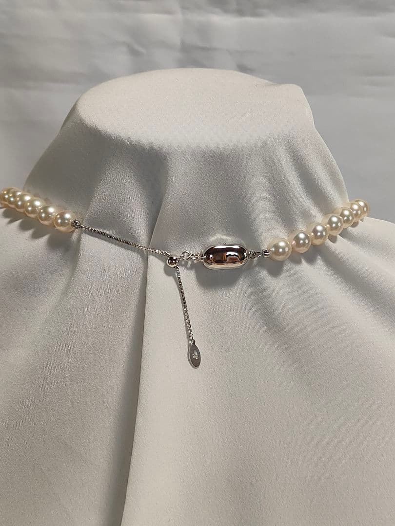 Akoya pearl necklace with white 7mm pearls and silver beans-shaped slide clasp on a plain background