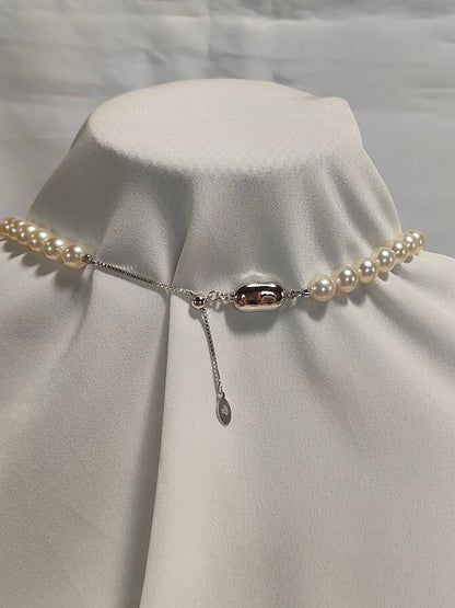 Akoya pearl necklace with white 7mm pearls and silver beans-shaped slide clasp on a plain background