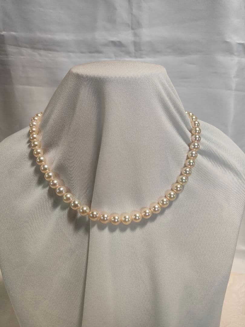 Akoya pearl necklace with white 7mm pearls and silver beans-shaped slide clasp on a plain background