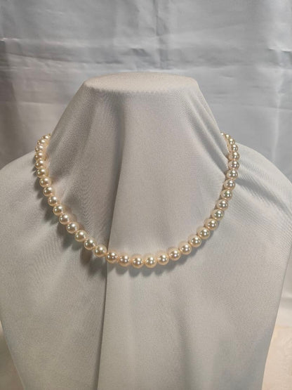 Akoya pearl necklace with white 7mm pearls and silver beans-shaped slide clasp on a plain background