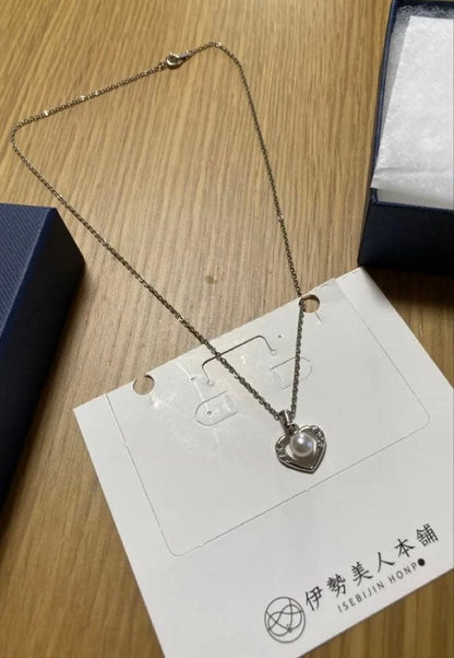 Heart-shaped silver necklace with white Akoya pearls on a white background