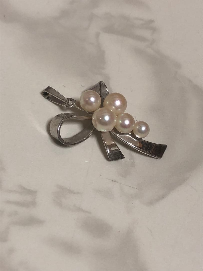 Silver ribbon-shaped pendant top adorned with five white pearls