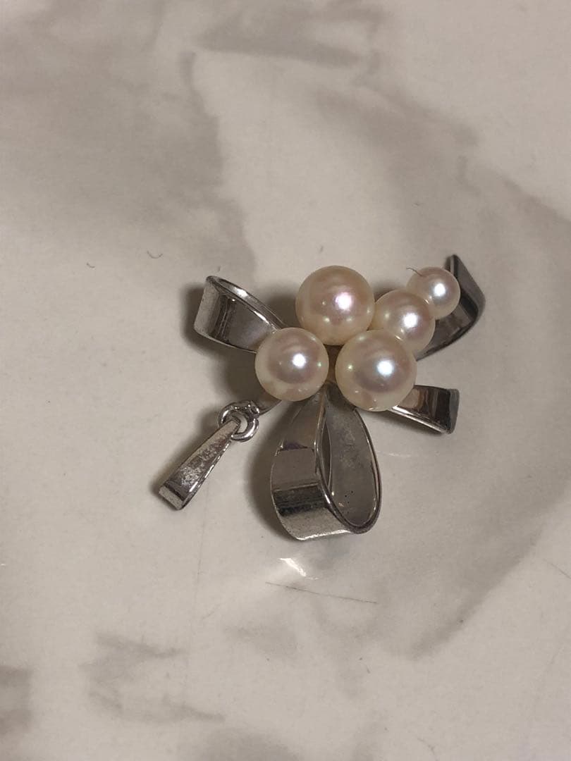 Silver ribbon-shaped pendant top adorned with five white pearls