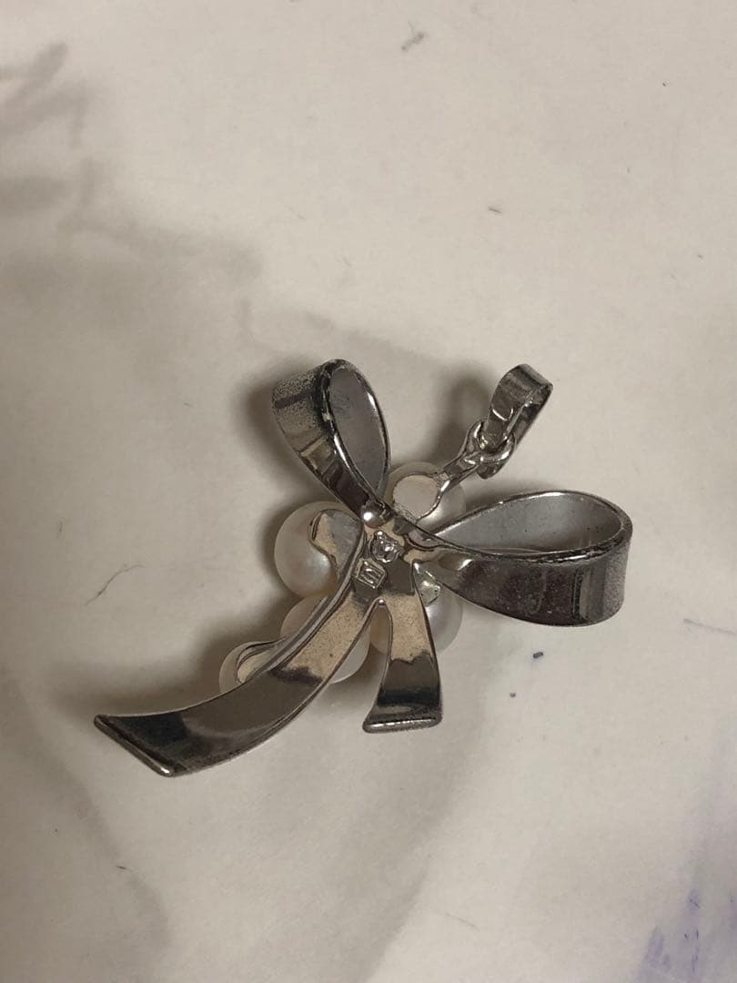 Silver ribbon-shaped pendant top adorned with five white pearls