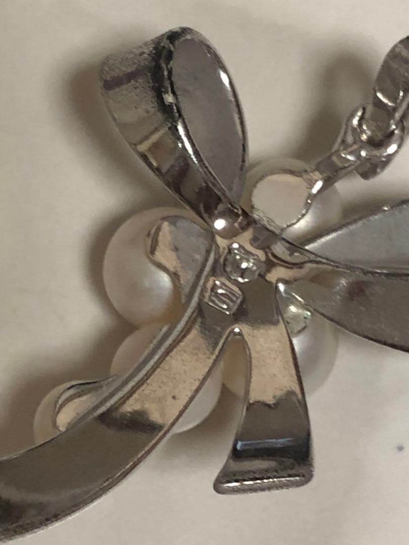 Silver ribbon-shaped pendant top adorned with five white pearls