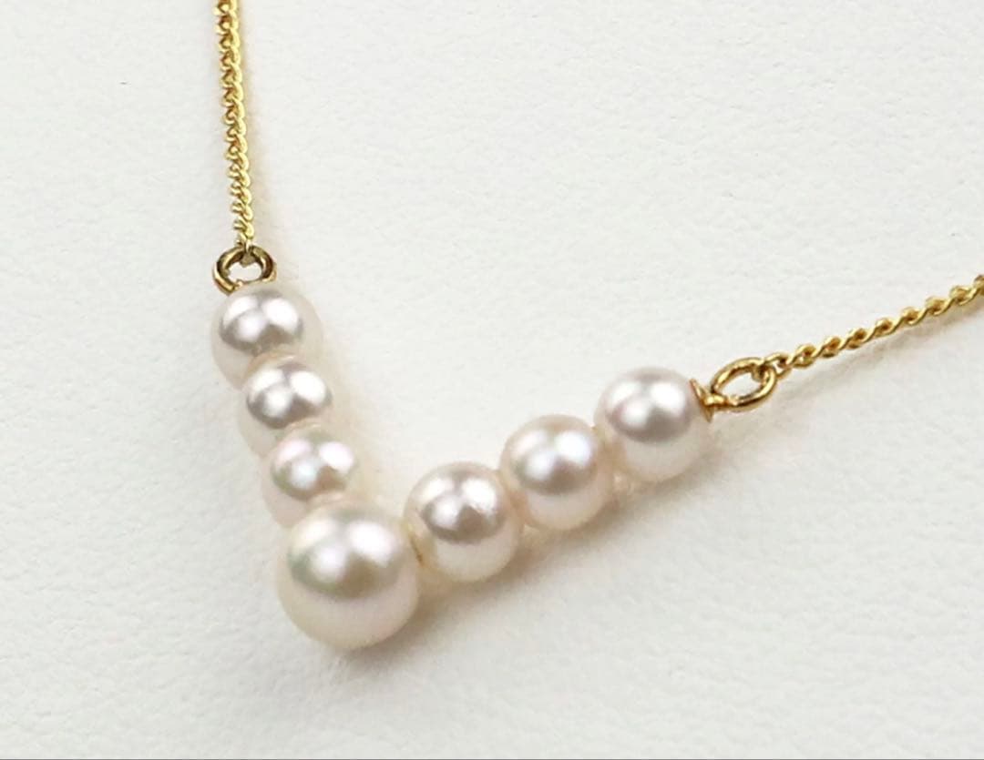 Akoya pearl necklace with V-shaped line and size-gradient pearls on a white background