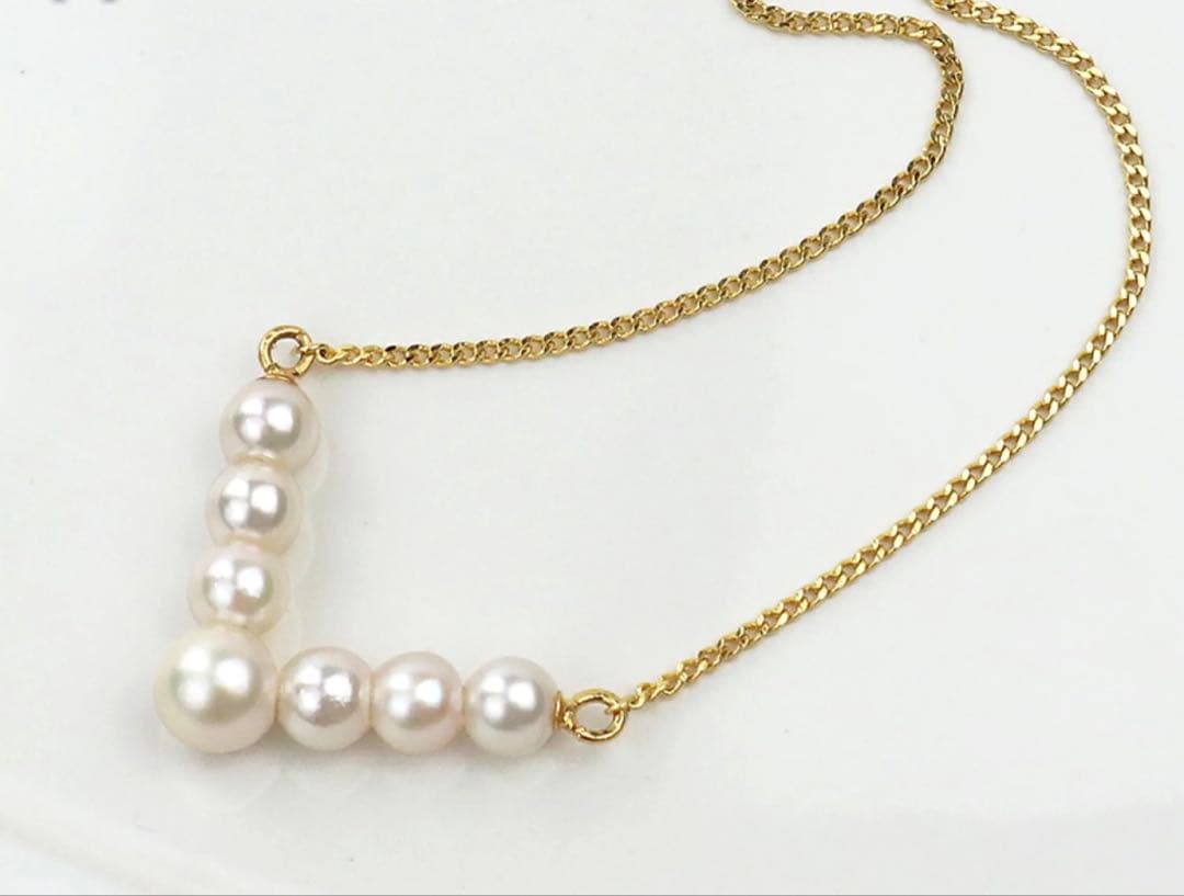 Akoya pearl necklace with V-shaped line and size-gradient pearls on a white background
