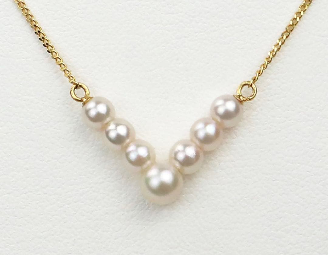 Akoya pearl necklace with V-shaped line and size-gradient pearls on a white background