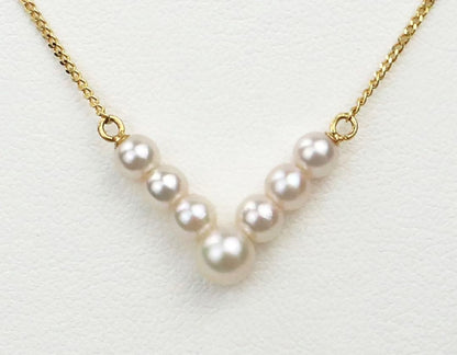 Akoya pearl necklace with V-shaped line and size-gradient pearls on a white background