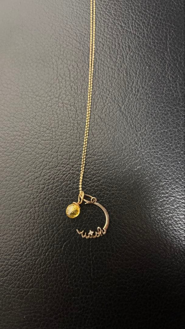Agete gold pendant top with crescent moon and star motif on a white background