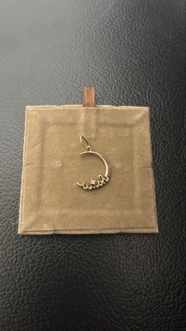 Agete gold pendant top with crescent moon and star motif on a white background